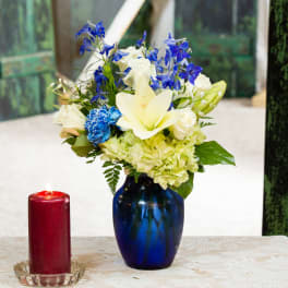 Blue and white flower arrangement in a cobalt vase beside a red candle