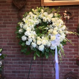 Large white floral wreath on a stand with a ribbon