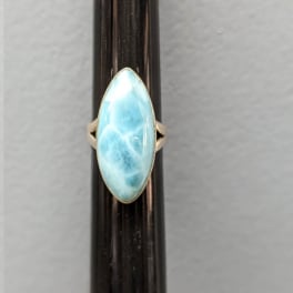 Oval blue gemstone ring on a dark display rod