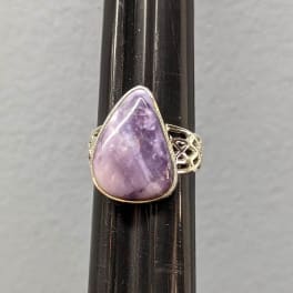 Purple teardrop gemstone ring on a dark display stand