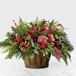 Holiday basket arrangement with pinecones, berries, and plaid ribbon