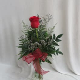 Single red rose arrangement in a clear glass vase with a red ribbon