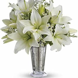 White lilies arranged in a tall silver vase
