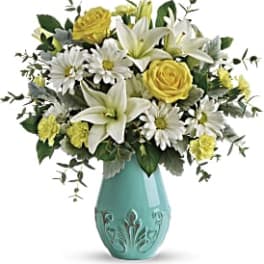 Yellow roses and white lilies in a turquoise vase