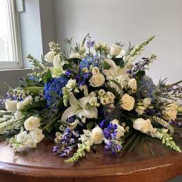 Large floral arrangement with white roses, lilies, and blue blooms on a table