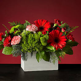 Red and pink mixed flower arrangement in a white box