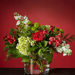 Red roses and white flowers arranged in a clear glass vase