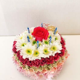 Round birthday cake made of flowers with a red rose and candles