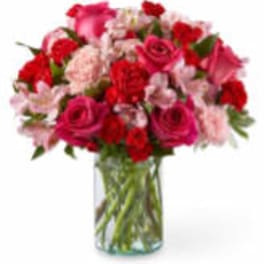 Pink and red roses with carnations in a clear glass vase