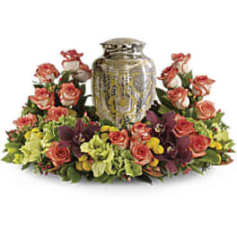 Floral arrangement of coral roses and orchids around a decorative urn