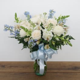 White and blue mixed bouquet in a glass vase with a pale blue ribbon