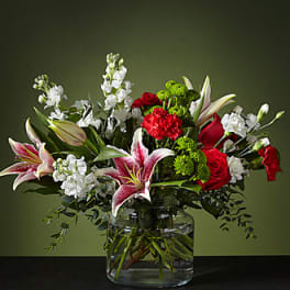 Bouquet of red roses, pink lilies, and white flowers in a glass vase