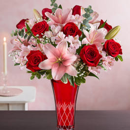 Red roses and pink lilies in a red glass vase