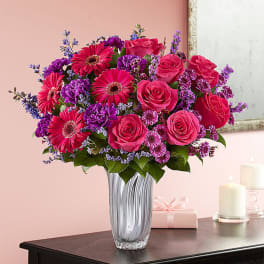 Pink roses and gerbera daisies in a clear glass vase