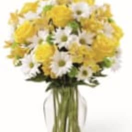 Yellow and white daisy bouquet in a clear glass vase