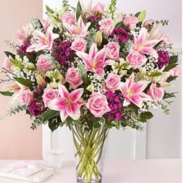 Pink roses and lilies arranged in a clear glass vase