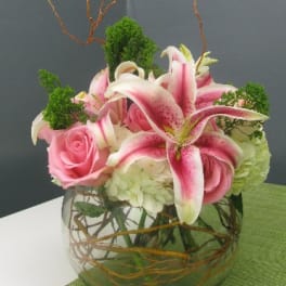 Pink roses and stargazer lilies in a round glass vase
