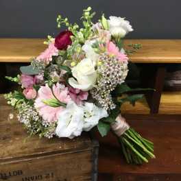 Hand-tied bouquet of pink and white flowers on a wooden surface