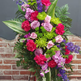Standing floral spray with pink roses, carnations, and purple blooms