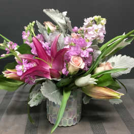 Pink lilies and roses arranged in a glass vase