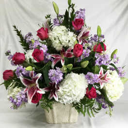 Large bouquet of pink roses, white hydrangeas, and purple lilies in a white vase