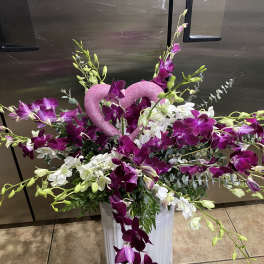 Purple and white orchid arrangement with a pink glitter heart in a white vase