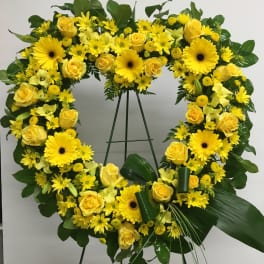 Yellow floral wreath on a stand with roses and daisies