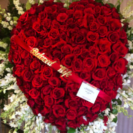 Heart-shaped red rose funeral wreath with white flowers around it