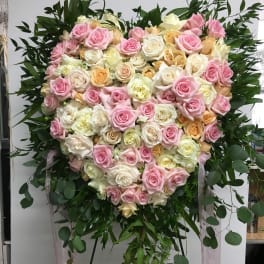 Heart-shaped arrangement of pink, white, and peach roses on a stand