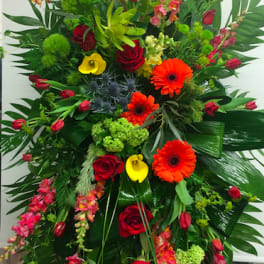 Tall mixed floral arrangement with red roses, orange gerberas, and yellow calla lilies
