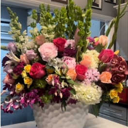 Large mixed bouquet in a white vase with pink, red, yellow, and purple flowers