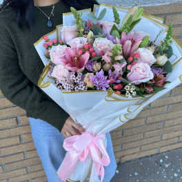Large bouquet of pink roses, lilies, and purple flowers wrapped in white paper