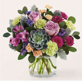 Mixed bouquet with roses, carnations, and a succulent in a glass vase