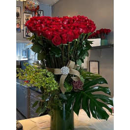 Large bouquet of red roses in a tall vase with a ribbon bow