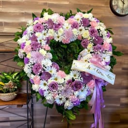 Heart-shaped floral wreath with pink, purple, and white flowers on an easel