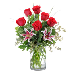 Red roses and pink lilies in a clear glass vase