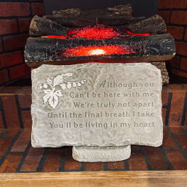 Decorative memorial plaque with an engraved poem in front of faux glowing logs