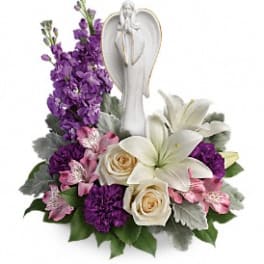 Purple and white floral arrangement with an angel figurine