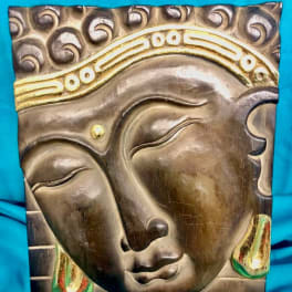 Decorative wall art with a Buddha face on a blue background