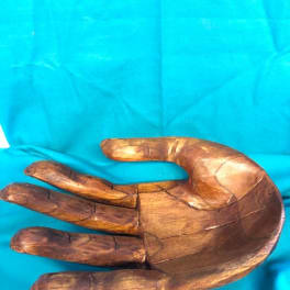 Wooden hand sculpture on a bright blue cloth background