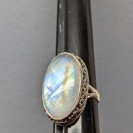Oval iridescent gemstone ring on a dark display stand
