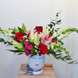 Bouquet of red and pink roses with lilies in a white face vase