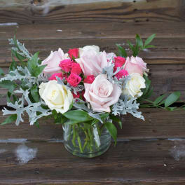 Pink and white roses in a glass vase with silver foliage