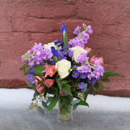 Bouquet of purple, pink, and white flowers in a clear glass vase