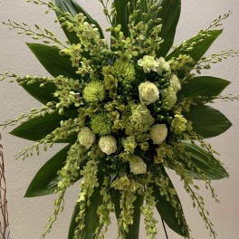 Large green floral spray with orchids and roses on a stand