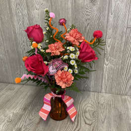 Pink roses and carnations in an amber vase with a striped ribbon