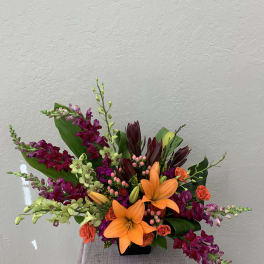 Orange lilies and magenta orchids in a black vase