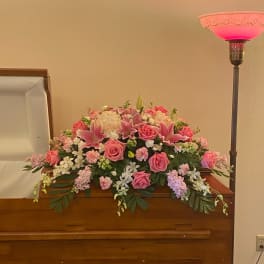 Pink and white floral arrangement on a wooden casket