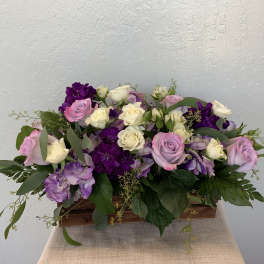 Pink, white, and purple roses in a low wooden box arrangement