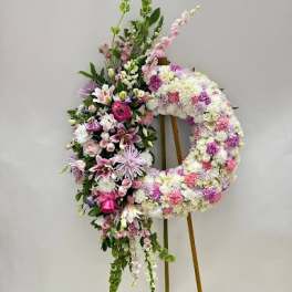 Floral standing wreath on an easel with pink, white, and purple flowers